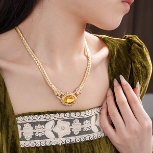 Detail of vintage snake chain necklace with gold oval yellow gemstone and sparkling rhinestones