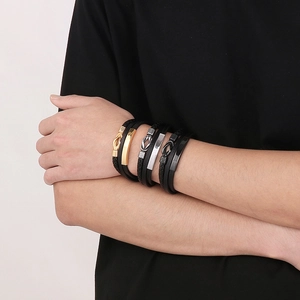 Détails de bracelets multicouches en cuir tressé avec des accents en métal or, argent et noir