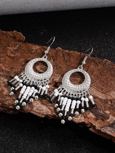 Detail of bohemian silver hollow carved earrings with black and white beaded tassels