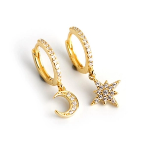 Detailed view of asymmetric gold star and moon drop earrings with micro-pave crystals