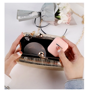 Detail view of gold pleated clutch interior showing capacity for powder and earphones