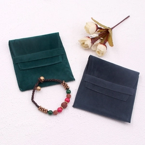 Detail view of dark green and navy blue suede jewelry pouches with a beaded bracelet
