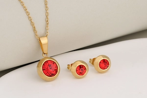 Detailed shot of gold-plated jewelry set with round red birthstones and matching earrings