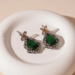 Macro shot of vintage pear-shaped green zircon earrings with orange butterfly accents