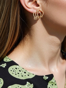 Close-up of golden multi-layer curved stud earrings with micro-pave cubic zirconia crystals