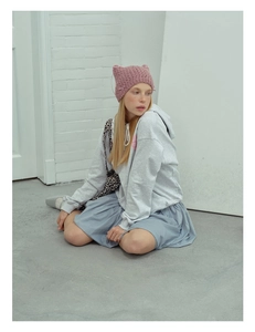 Detail of pink crochet cat ear knit hat with bow tie texture on a seated model