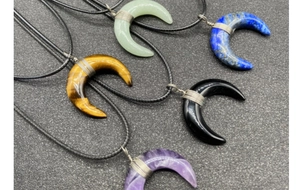 Flat lay of five crescent moon gemstone necklaces with wire wrap details and braided ropes