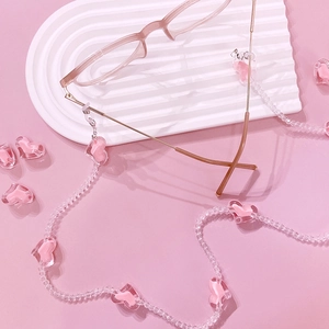 Detailed macro view of pink heart acrylic eyeglass chain on a rippled aesthetic tray