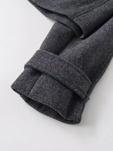 Detailed macro view of dark grey wool jacket cuff with decorative strap and stitching