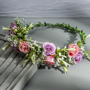 Detail shot of pink and purple silk roses with green leaves on a handmade bridal floral headband