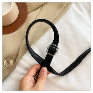 Detail view of the black leather shoulder strap with a silver adjustable metal buckle