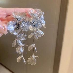 Macro shot of sparkling silver flower tassel earrings with crystals and acrylic petals