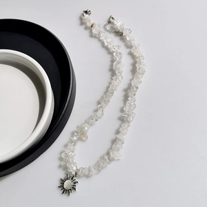 Macro detail of sun pendant with crushed stones on a silver-toned clavicle chain