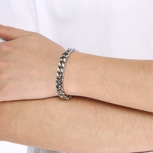 Close-up of polished silver Cuban link chain bracelet worn on a person's wrist