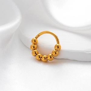 Detailed view of a golden beaded seamless hoop earring on a white textured background