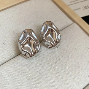 Macro shot of silver irregular geometric metal earrings in a beige jewelry box liner