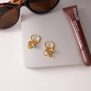 Intertwined gold and silver stainless steel hoop earrings in a layered minimalist design