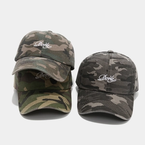 Close-up of Dorie embroidery on vintage washed camo baseball caps in green and grey