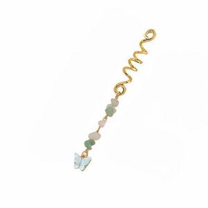 Detail of ethnic golden spiral hair ring with green stone beads and blue resin butterfly