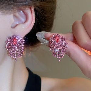 Detailed view of pink rhinestone fringe earrings with ruby-colored center stone