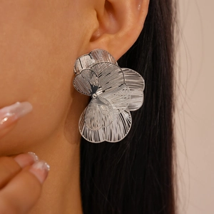 Close-up of a silver hollow flower earring worn on a model, showing metal craftsmanship