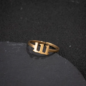 Detailed view of golden stainless steel gothic number ring on black rock surface