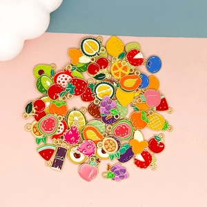 Detailed top view of assorted colorful enamel fruit charms on a pink background