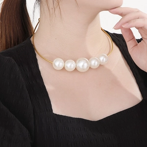 Detail of a gold choker with five gradient white pearls on a model wearing black clothing