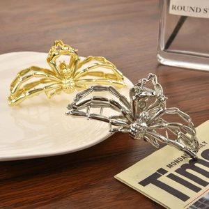 Detail of gold and silver spider hair claws in high-polish alloy with a gothic aesthetic