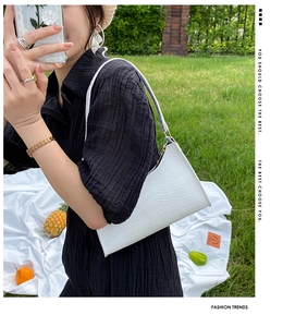 White crocodile pattern shoulder bag shown in a sunny outdoor summer picnic scene