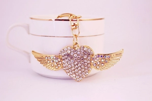 Macro detail of gold-tone heart keychain with sparkling rhinestones and wings