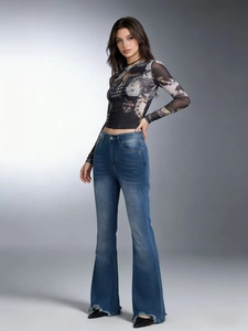 Women's flared denim jeans with ripped hem paired with a long sleeve printed mesh top