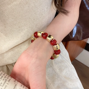 Detailed shot of beaded bracelet with red shimmer beads and gold geometric metal accents