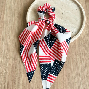 Detail of USA flag pattern scrunchie with ribbons on a beige tray over wooden desk