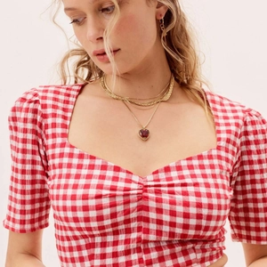 Elegant gold layered necklace with a red heart gemstone pendant on a female model
