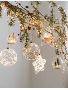 Close-up of glowing glass Christmas ornaments with LED lights and miniature scenery