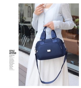 Detail view of water-resistant navy blue nylon handbag with silver metal hardware and strap