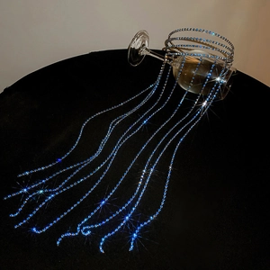 Detail of blue rhinestone fringe chains draped over a glass on dark background