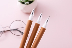 Detailaufnahme von drei orangefarbenen Bärenstiften mit Nadelspitzen auf rosa Hintergrund