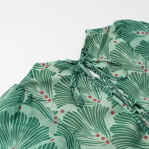 Close-up of green floral print dress showing tie-neck detail and leaf pattern fabric