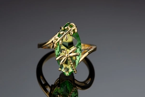 Vista macro dell'anello con gemma marquise verde oliva e dettagli di libellula dorata