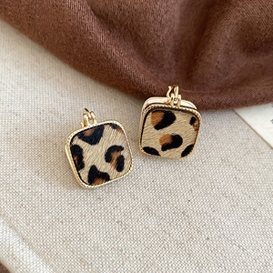 Dettaglio degli orecchini quadrati leopardati con cornice in oro 18K su tessuto morbido