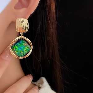 Close-up of vintage geometric resin earrings with green gemstone on a fashion model