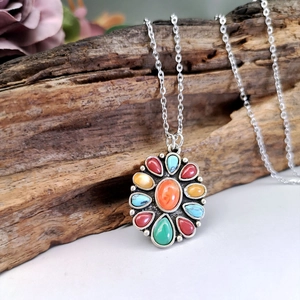 Bohemian silver necklace with colorful agate and turquoise stones on a natural wood log