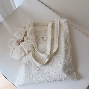 Close-up of cream cotton tote bag with floral embroidery and matching scrunchie set