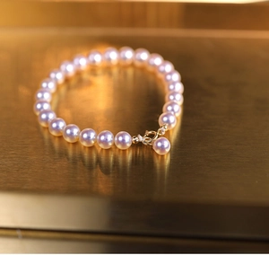 Close-up of elegant pearl bracelet with golden clasp on a warm metallic background