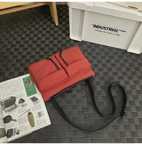 Nylon messenger bag in rust red with dual utility pockets and tactical bungee cords