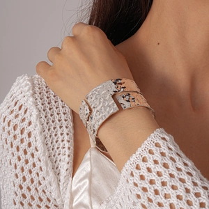 Detailed close-up of wide silver textured cuff bracelet with irregular geometric pleats