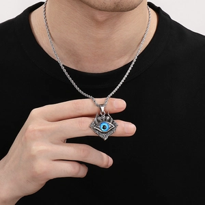 Dettaglio del pendente a teschio con occhio blu e catena intrecciata da uomo