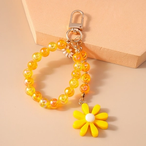 Detailed macro view of a beaded keychain with yellow flower charm and metal clasp hook